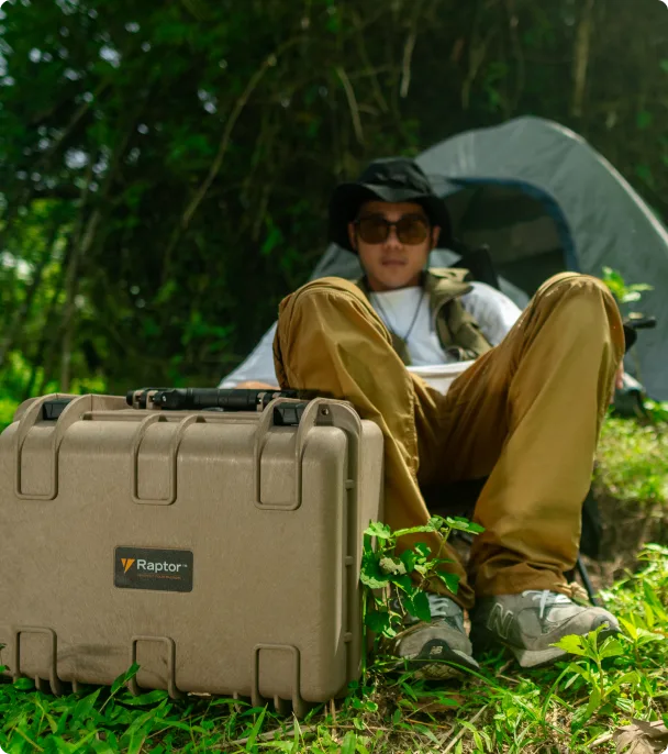 Person sitting outdoors with a Raptor case next to them